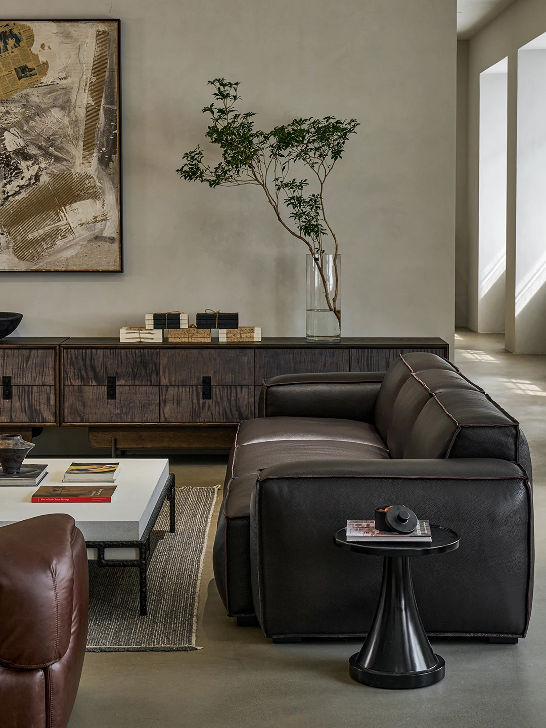 Long dark timber Kasane sideboard behind a low Kaku leather sofa