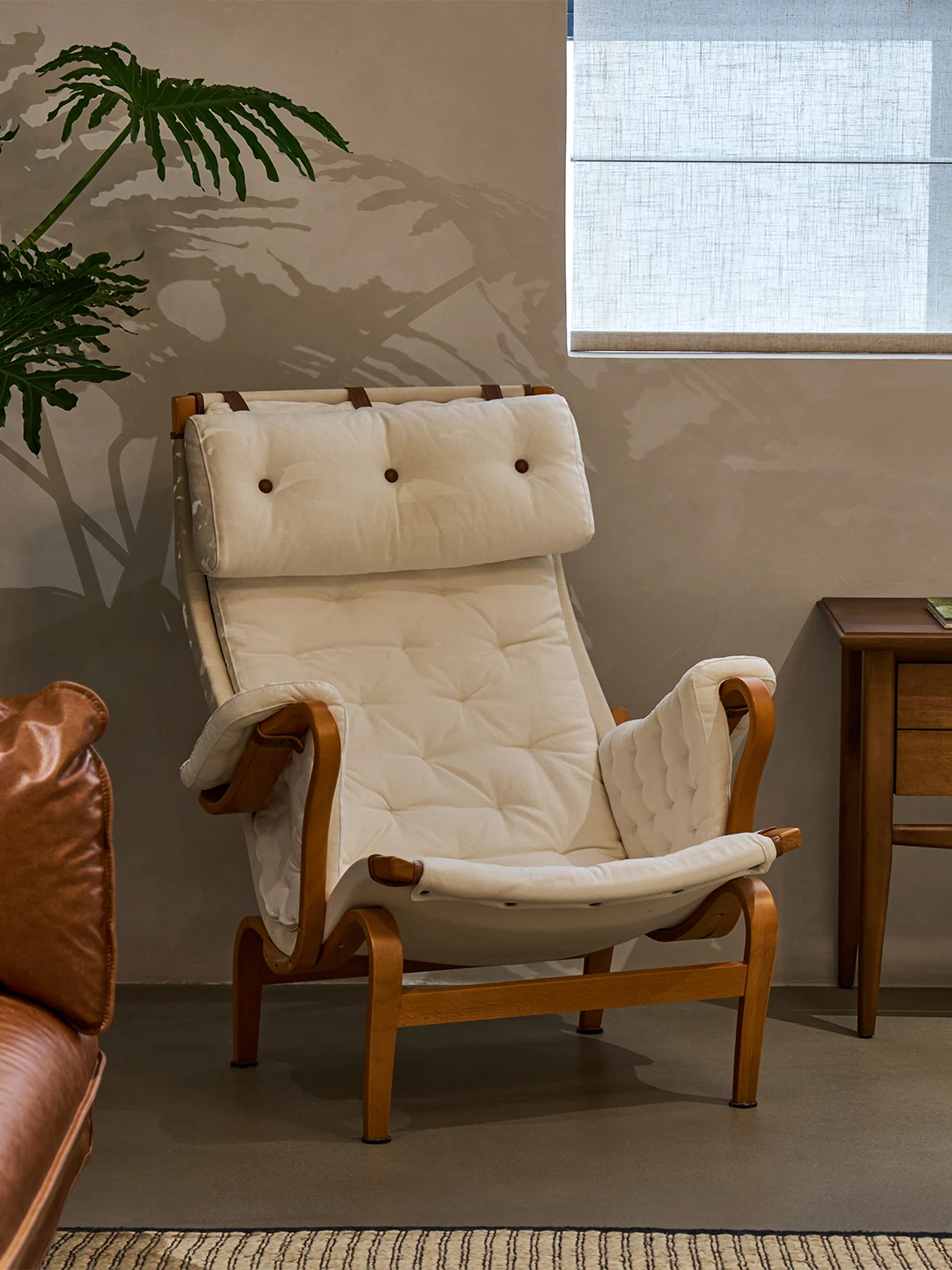 Cream quilted Nera lounge chair beside a timber cabinet