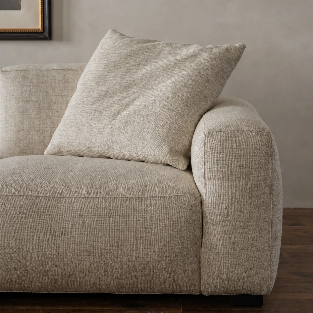 Close detail of the Kaku sofa arm, cushion and low timber foot